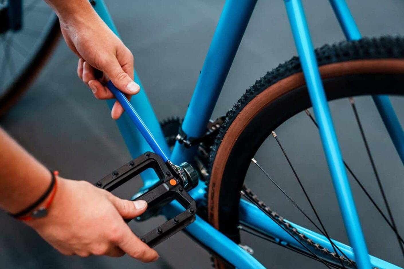 Ein Pedal wird mit dem Schlüssel in den Kurbelarm gedreht
